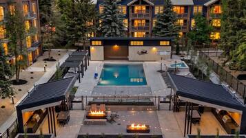 A hotel with a swimming pool, outdoor seating, and a covered patio area.