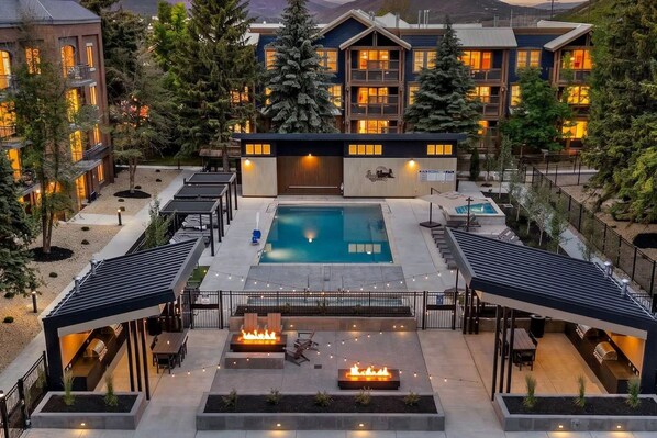 A hotel with a swimming pool, outdoor seating, and a covered patio area.