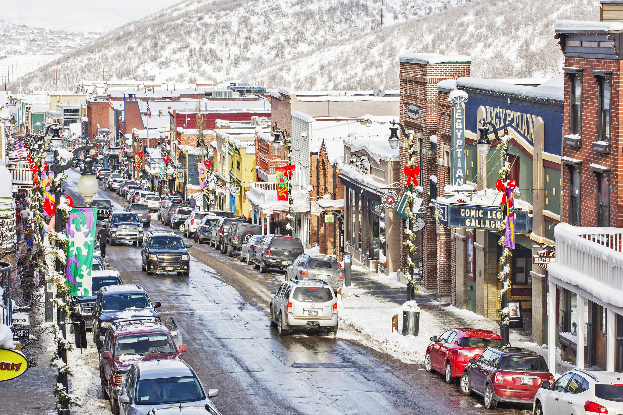 A snowy urban street lined with various shops and buildings.