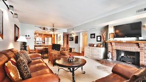 A spacious living room with leather sofas, a coffee table, and a fireplace.