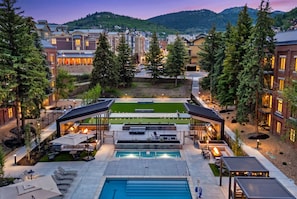A resort with a swimming pool, outdoor seating, and a view of the surrounding buildings.