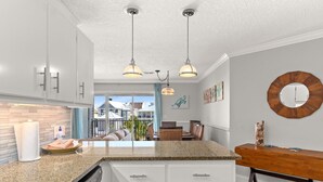 A modern kitchen with granite countertops, white cabinetry, and pendant lighting. - Spacious 3 bed 2.5  ba unit, close to the beach, heated pool, tennis, pickle bal (Santa Rosa Beach)