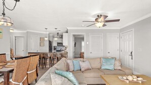 A living room with a sectional sofa, dining table, wicker chairs, and a ceiling fan. - Spacious 3 bed 2.5  ba unit, close to the beach, heated pool, tennis, pickle bal (Santa Rosa Beach)