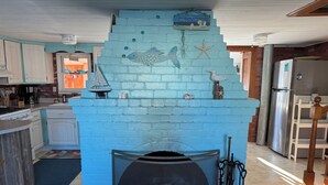 Une cuisine avec un mur en briques bleues, une fresque représentant des poissons et un réfrigérateur en acier inoxydable.