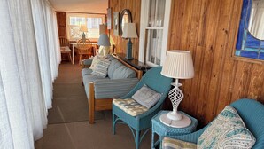 Une pièce chaleureuse avec un mur en bois, un canapé, deux petites tables de chevet avec des lampes et un fauteuil.
