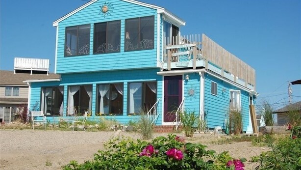 Une maison à deux étages dotée d’un balcon imposant et d’un petit porche.
