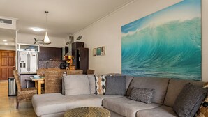 Ein Wohnzimmer mit einer Couch, einem runden Couchtisch und einem großen Wandbild mit dem Motiv einer Welle.