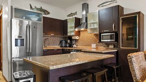 Eine moderne Küche mit Edelstahlgeräten, einer Granitabdeckung und Barhocker.