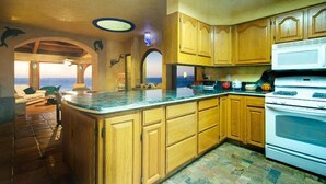 Una cucina con mobili in legno, un'isola grande e vista sull'oceano.