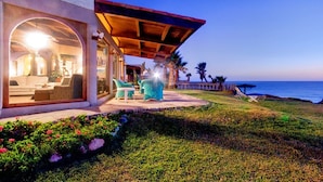 Una proprietà costiera con patio coperto, area salotto esterna e vista sull'oceano.