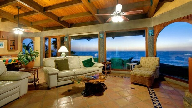 Un ampio soggiorno con vista sull'oceano, una ventola a soffitto e una zona pranzo con tavolo e sedie.