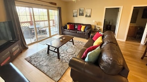 Un salon spacieux avec un canapé en cuir, une table basse et un ventilateur de plafond.