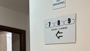 Hotellihuone, jossa on kyltti, joka kieltää tupakoinnin, sekä opastekyltti huoneisiin 7, 8 ja 9.