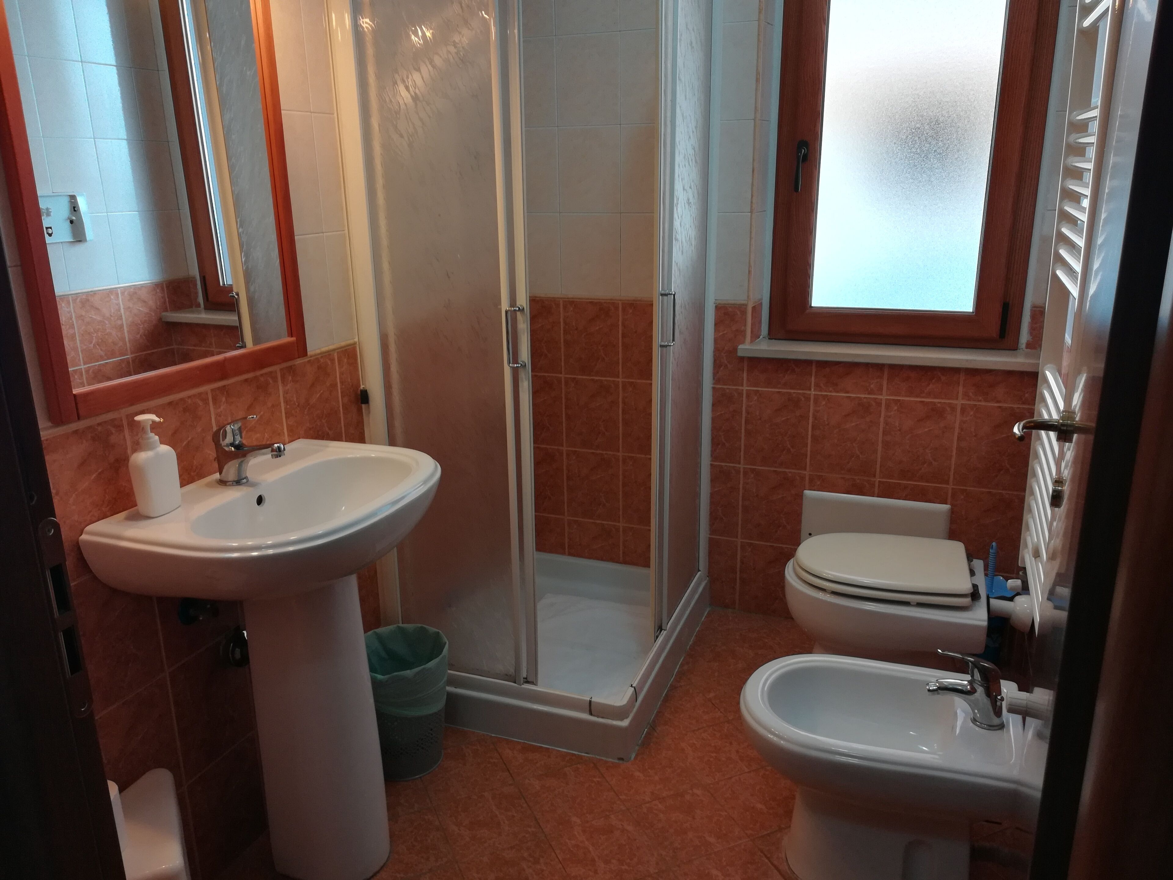 A bathroom with a shower, two sinks, and a toilet.