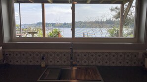 Cuina amb una finestra gran que dona a un llac, un obrador d'acer inoxidable i rajoles decoratives a la cantonada.