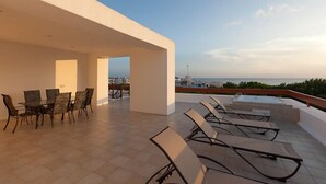 Una terrazza panoramica con zona pranzo e poltrone relax, con vista sulla città e sul mare.