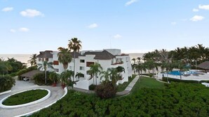 Un resort con piscina, palme e vista sull'oceano.