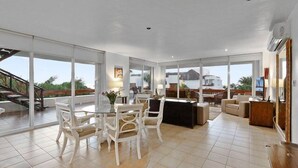 Un'ampia zona giorno con tavolo da pranzo, angolo bar e grandi porte scorrevoli in vetro che danno su un balcone.