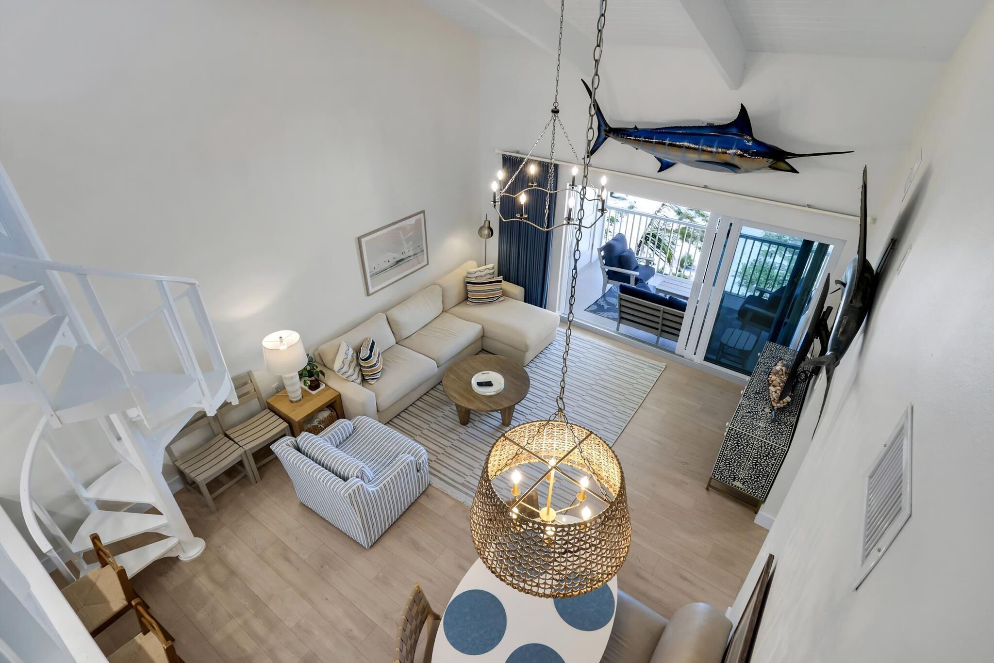 A spacious living area with a staircase, a hanging light fixture, and a large fish decoration.