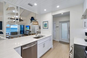 A modern kitchen with a large island, built-in appliances, and a view to the outside.