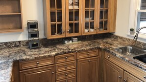 A kitchen with wooden cabinets, granite countertops, and a stainless steel sink. - Modern! Professionally Cleaned, Self Check In - Sleeps 10 (Kenosha)