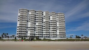 Een hoog hotel met meerdere balkons, direct aan het strand.