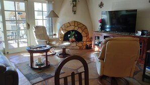 A living room with a stone fireplace, a television, and comfortable seating.