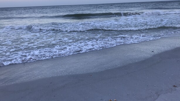 En strand där vågorna försiktigt sköljer in mot land.