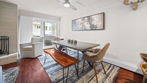 Et spiseområde med et bord, stole, en bænk, en loftsvifter og et indrammet billede på væggen.