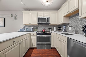 A modern kitchen with white cabinets, stainless steel appliances, a microwave, stove, and a dishwasher. - 100 Steps to Gondola! A/C, Steps to multiple restaurants, shops, and rentals! (Vail)