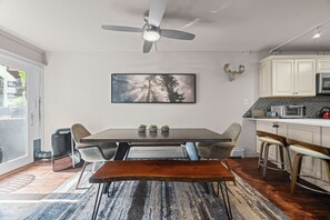 A modern kitchen with a dining area, a ceiling fan, a large window, and a kitchen island. - 100 Steps to Gondola!  A/C, Steps to multiple restaurants, shops, and rentals! (Vail)