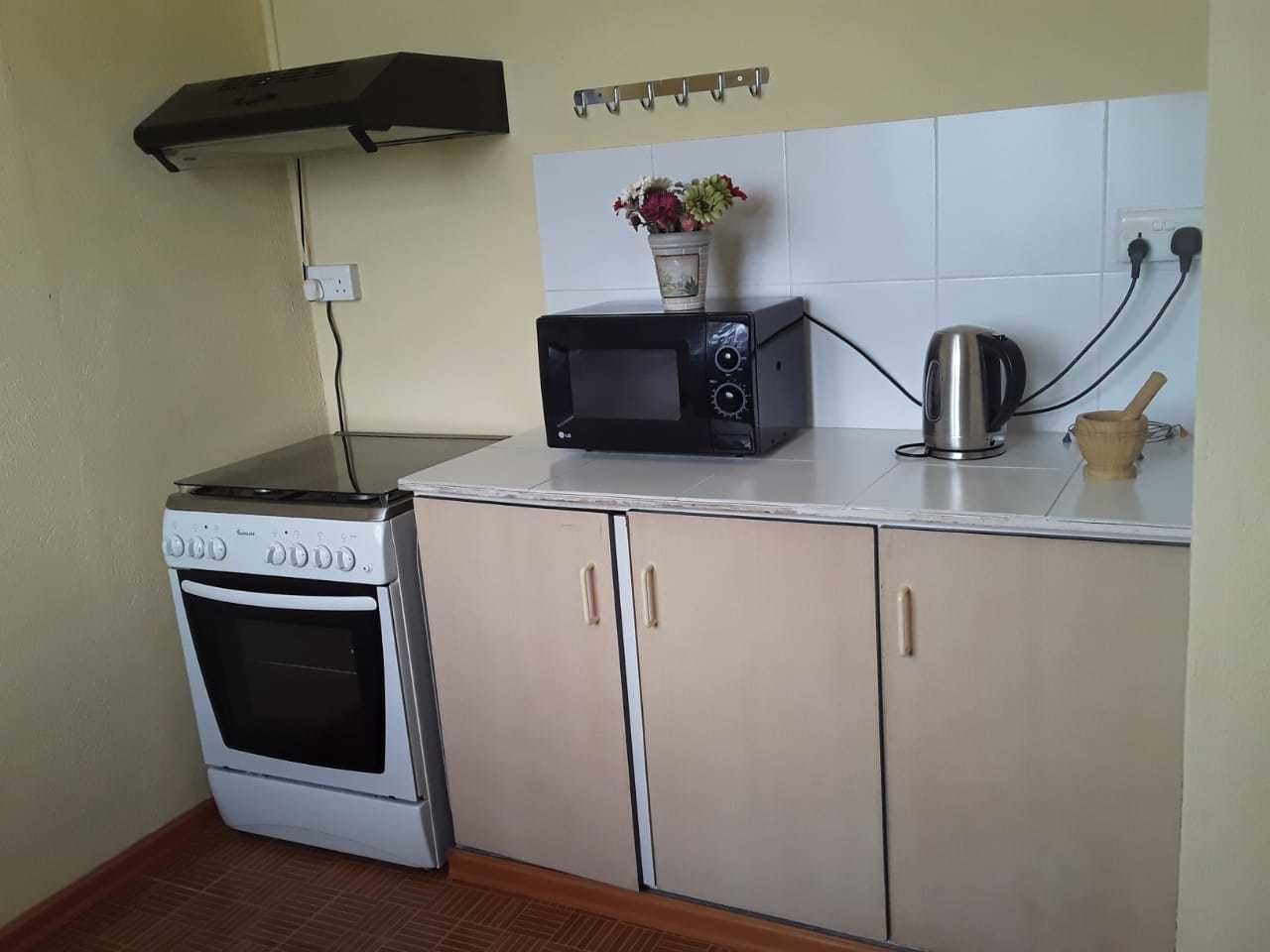 A compact kitchen with a stove, microwave, and cabinets.