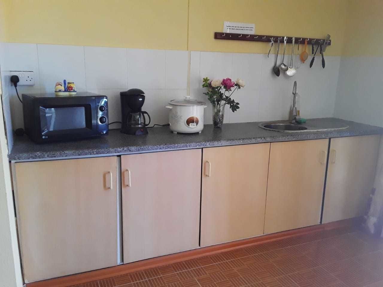 A kitchen with a microwave, coffee maker, and a slow cooker on the counter.