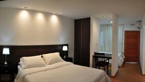 A hotel room with a large bed, a nightstand with a lamp, a wooden wardrobe, a desk with a chair, and a wooden floor. - L'Hirondelle - Adults Only (La Falda)