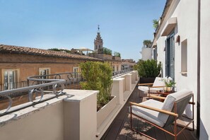 A balcony with outdoor furniture, a view of the cityscape, and a building with a tower in the background.