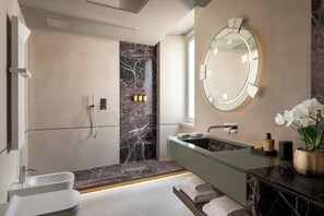 A modern bathroom with a glass-enclosed shower, a marble-tiled vanity, and a large mirror.