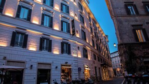 Un edificio de varios pisos con ventanas iluminadas y una calle empedrada.