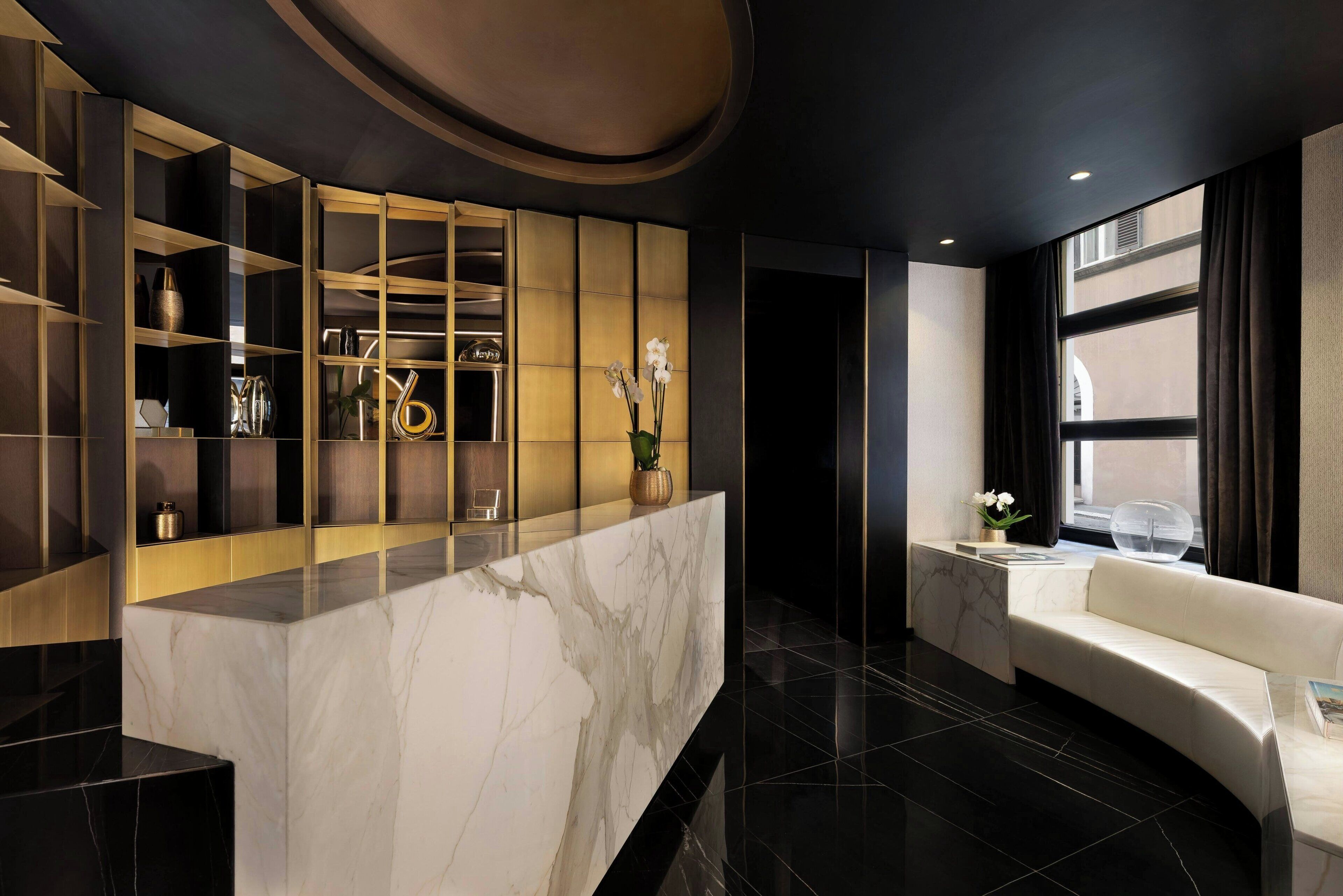A modern lobby with a marble reception desk, a sofa, and a large window with curtains.