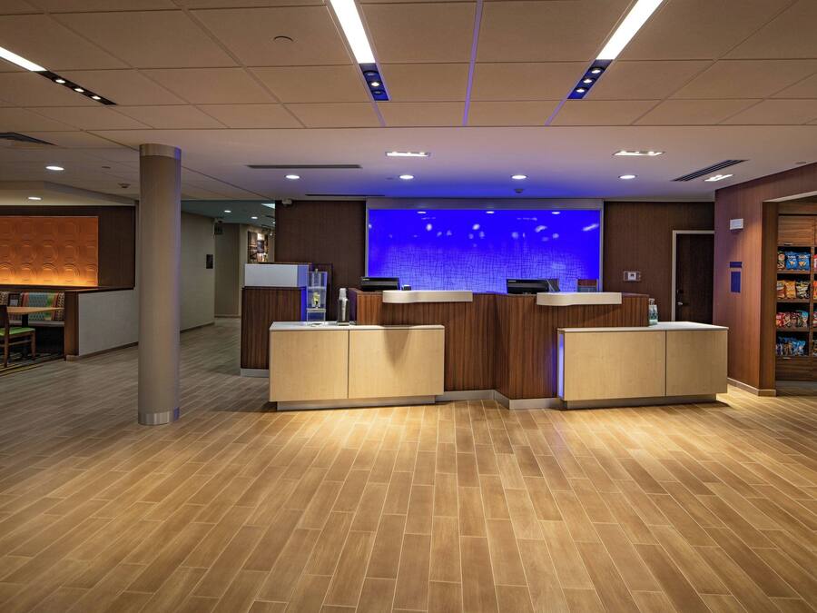 A reception area with a wooden floor, two reception desks, a blue wall with a grid pattern, and a snack bar with packaged goods.