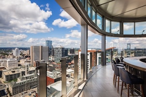 A high-rise building with a panoramic city view from a balcony.
