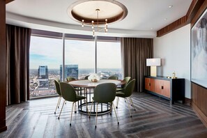 A modern hotel room with a large round table, four chairs, a wooden cabinet, and a large window offering a city view. - JW Marriott Nashville (Nashville)