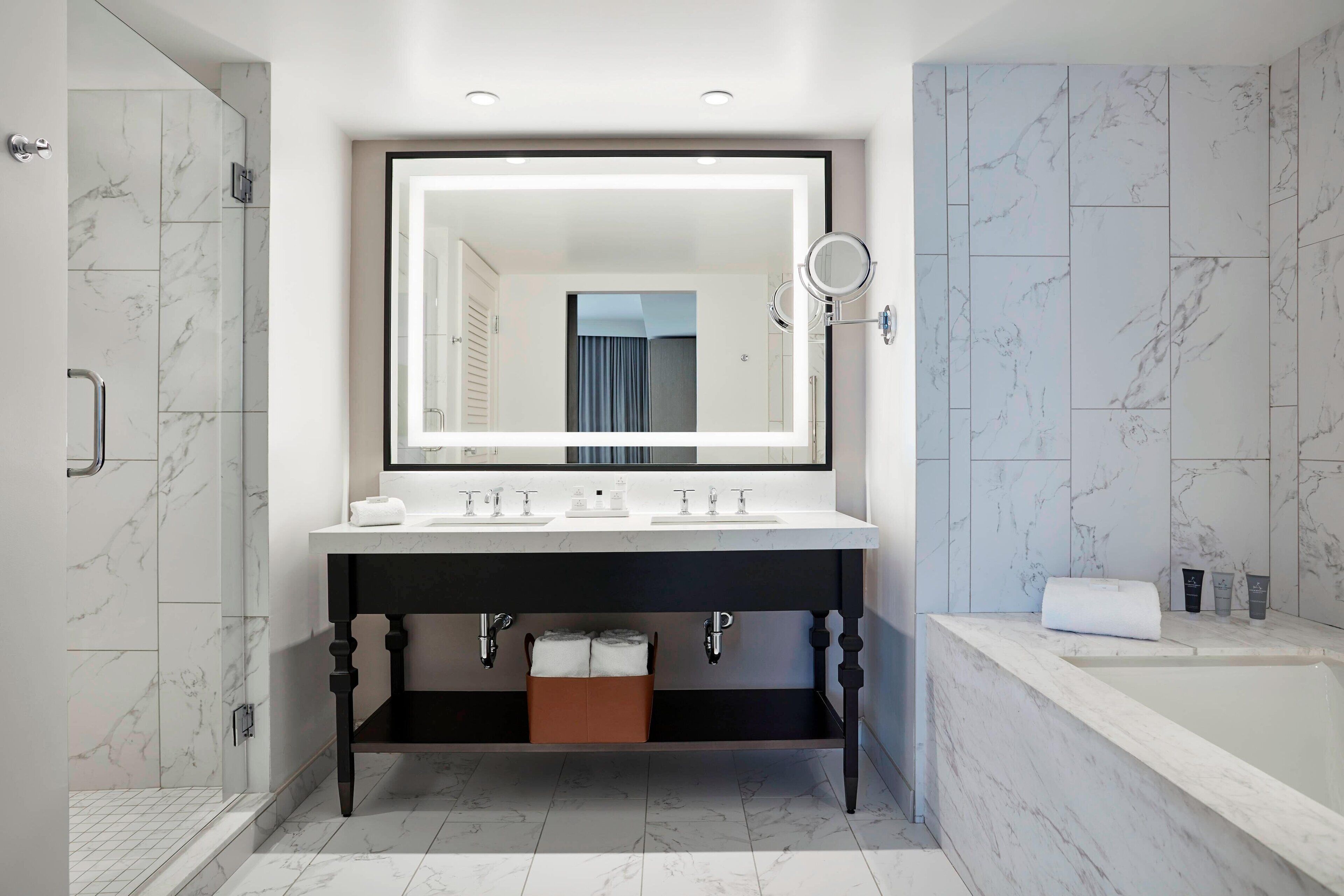 Un baño moderno con un espejo grande, dos lavamanos, una bañera y una ducha a ras de suelo.