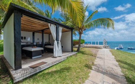 A covered outdoor seating area with a pool table, a small bar area, and a view of the ocean.