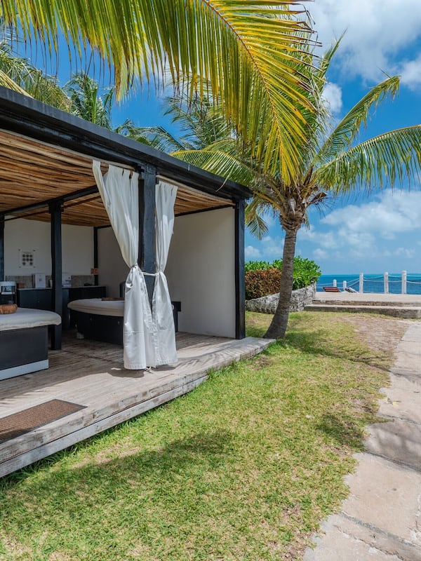 Relax by the pool, surrounded by palm trees and a serene ocean view.