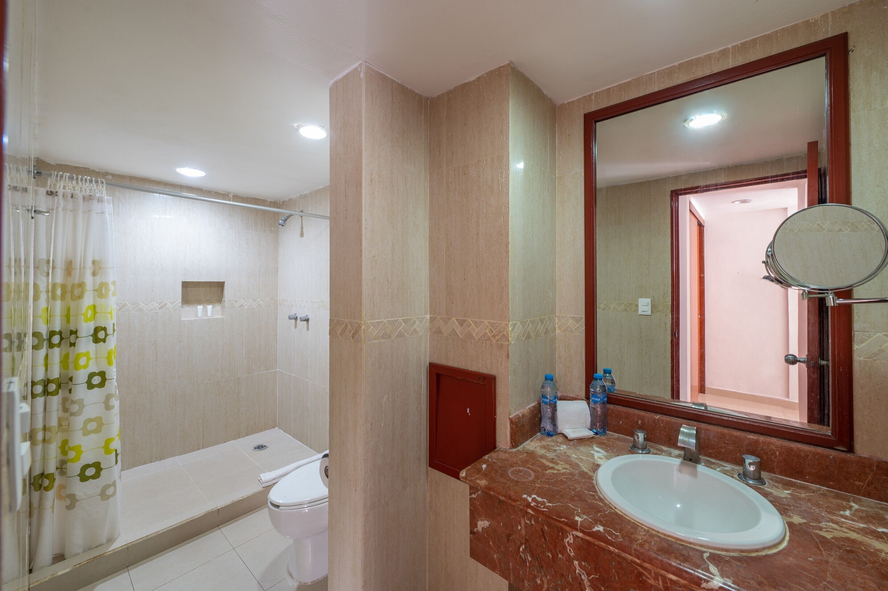 Un baño con ducha, inodoro, lavamanos y espejo.