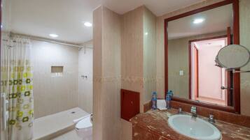 Un baño con ducha, inodoro, lavamanos y espejo.