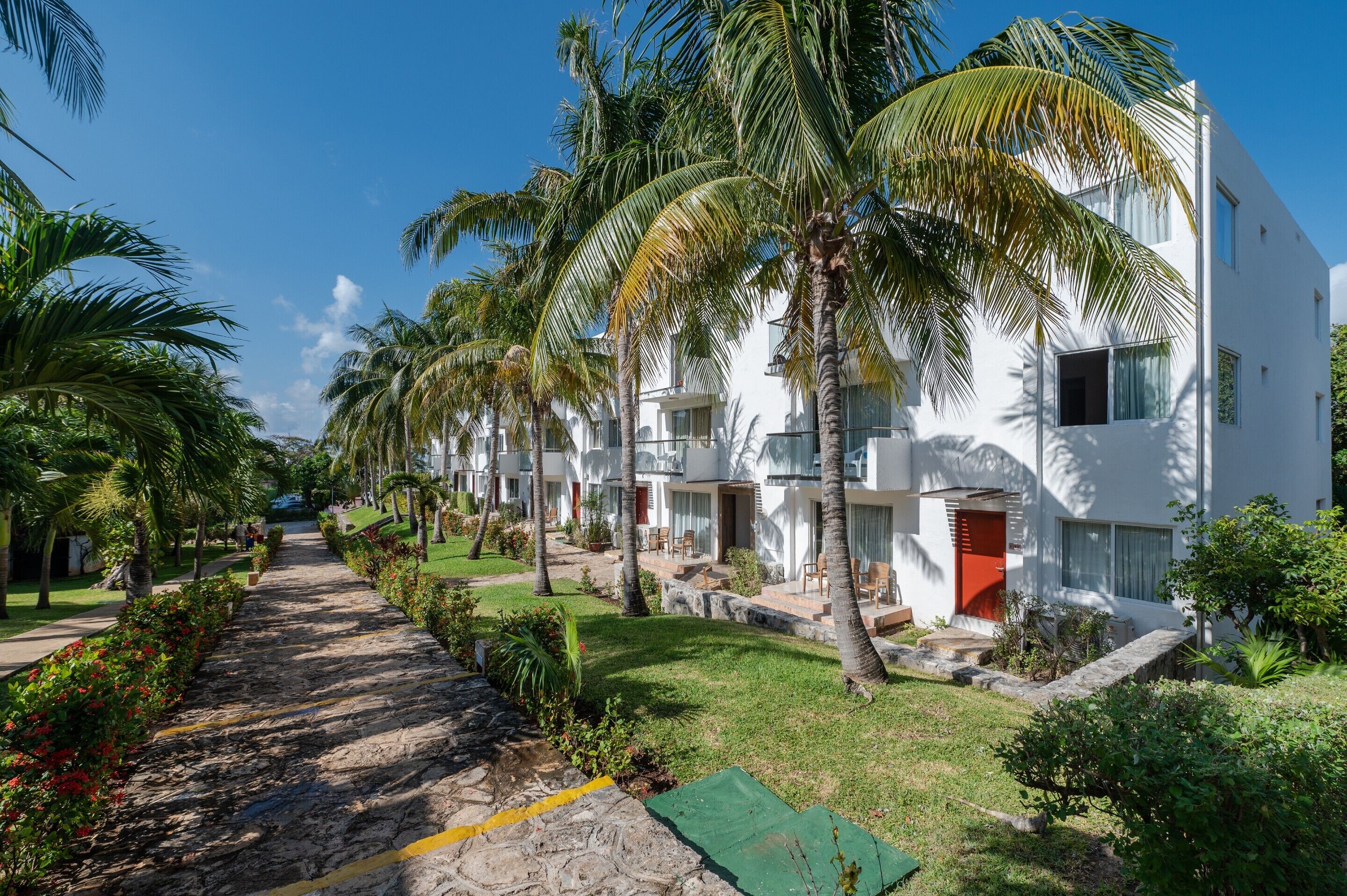 Un resort con edificios blancos, palmeras y un paseo pavimentado.