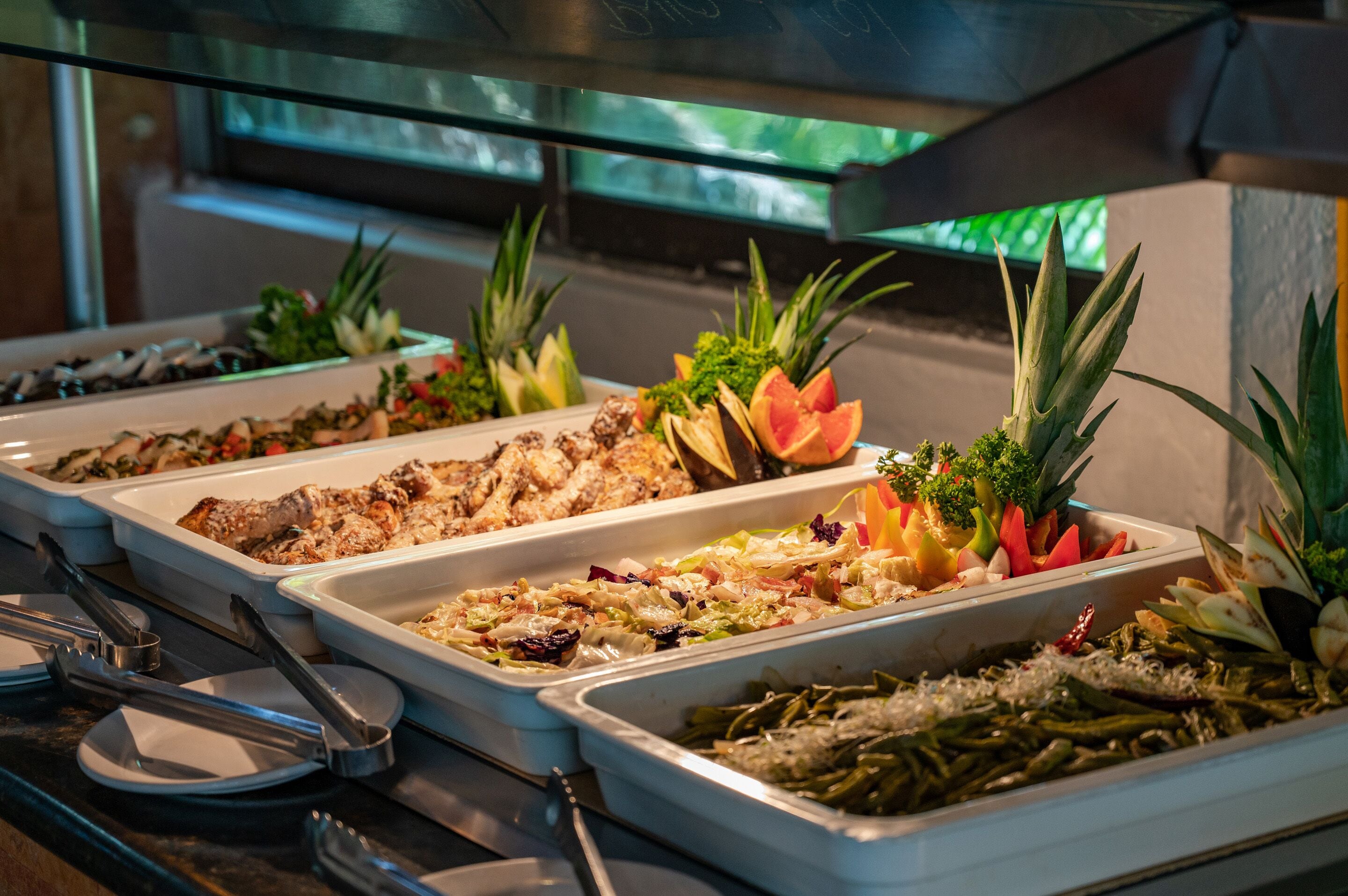 Buffet com diversos pratos, incluindo carnes, saladas e legumes.
