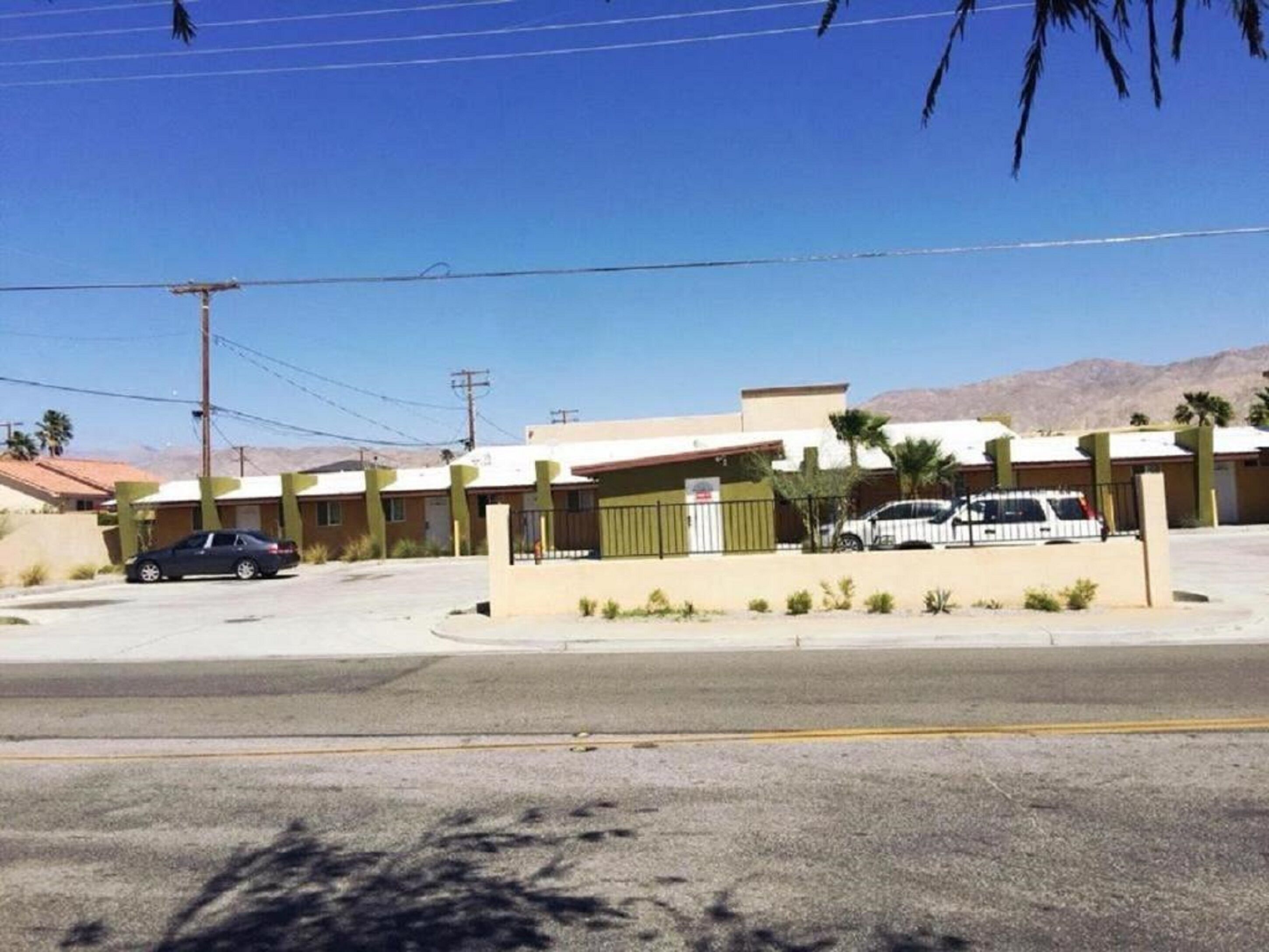 Un motel con estacionamiento, un edificio de una sola planta y una montaña al fondo.