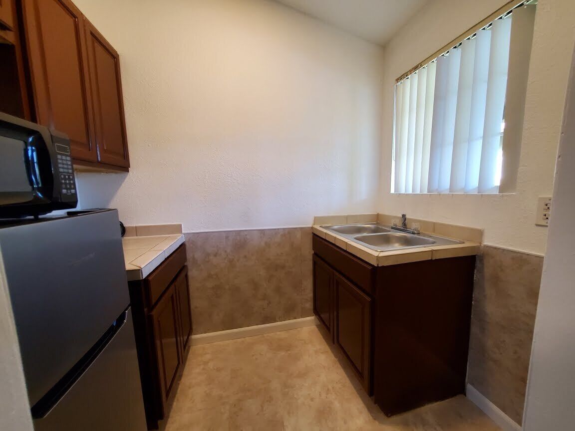 A compact kitchen with a microwave, sink, and cabinets.